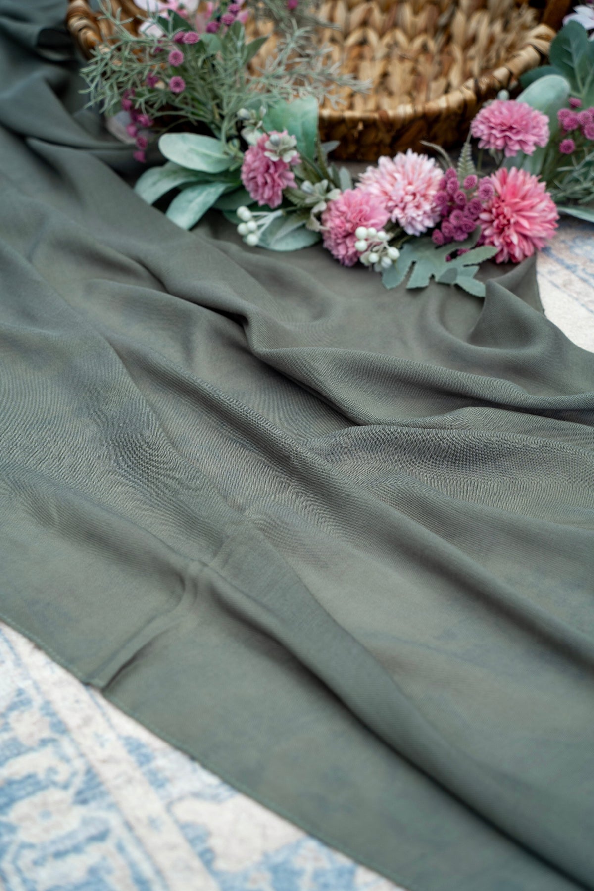 Green fabric with pink flowers and greenery on a textured surface