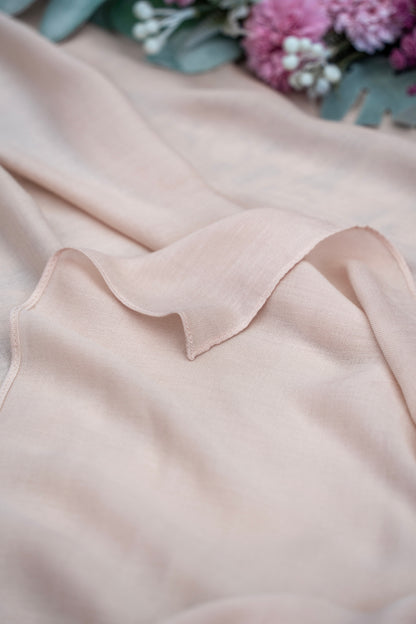Close-up of a light pink sleeveless top with a collar, blurred flowers in the background.