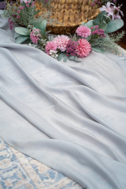 Light gray fabric with pink flowers and a woven basket on a textured surface