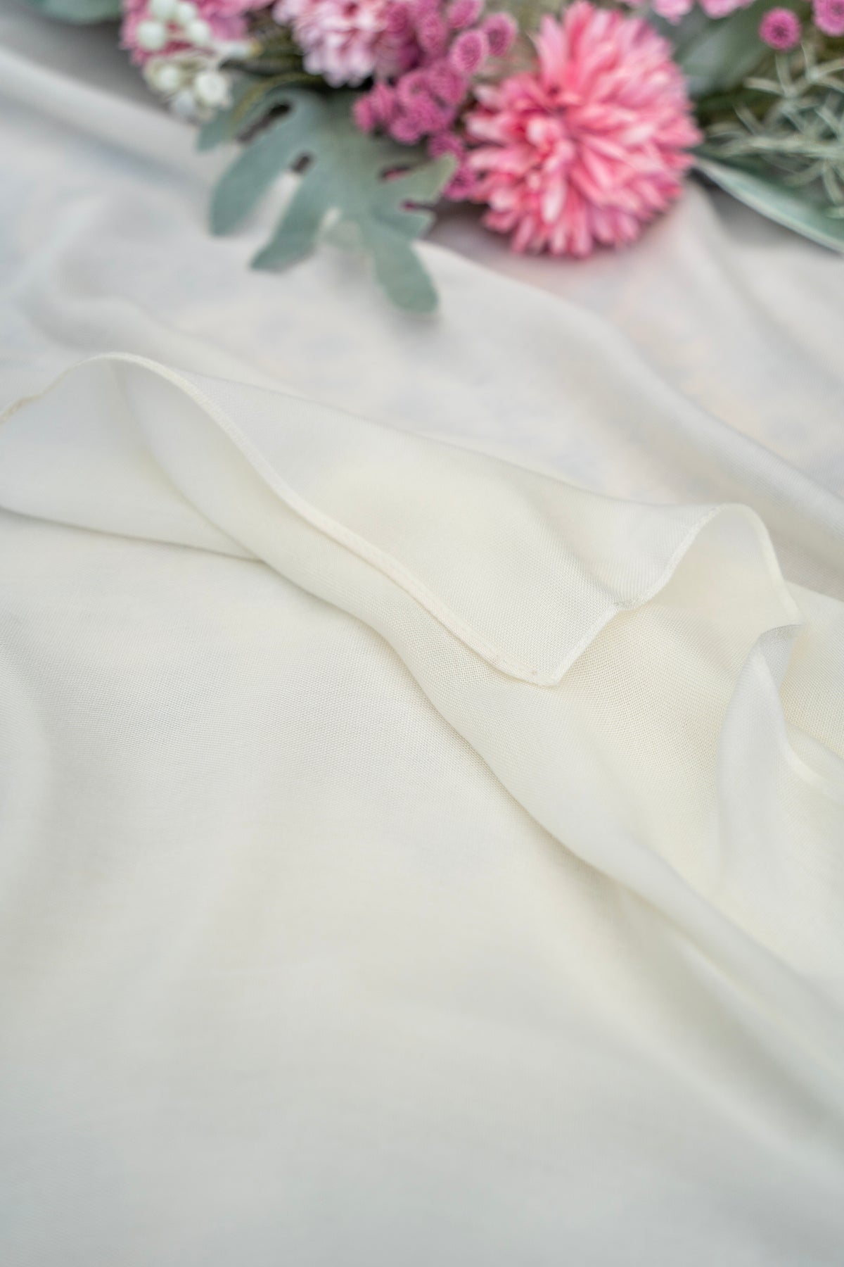 White fabric with pink flowers and green leaves on a light background