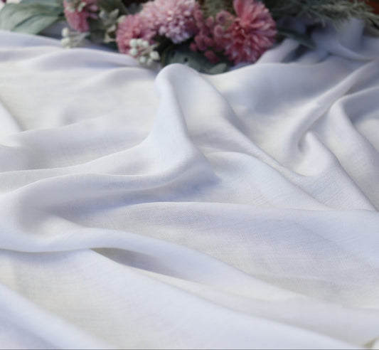 White fabric with pink flowers and green leaves on a textured surface