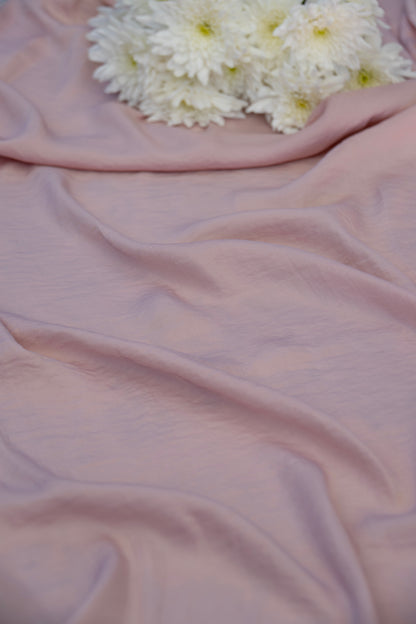 Dusty pink draped fabric with soft folds and a cluster of white chrysanthemums placed in the upper corner.