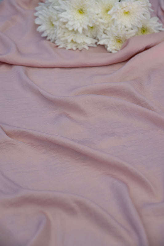Dusty pink draped fabric with soft folds and a cluster of white chrysanthemums placed in the upper corner.