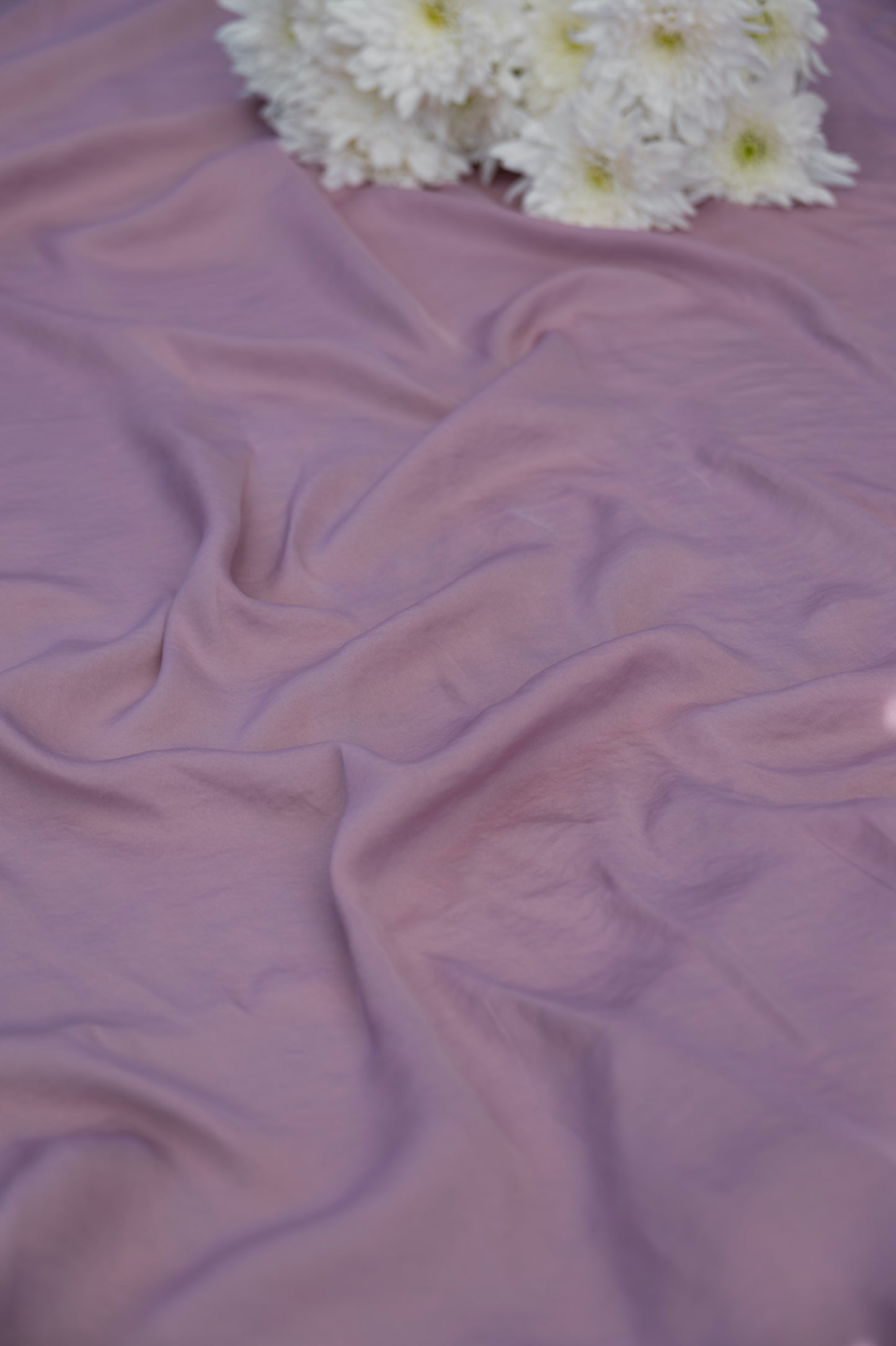 Lavender purple draped fabric with white daisy flowers in the top corner.