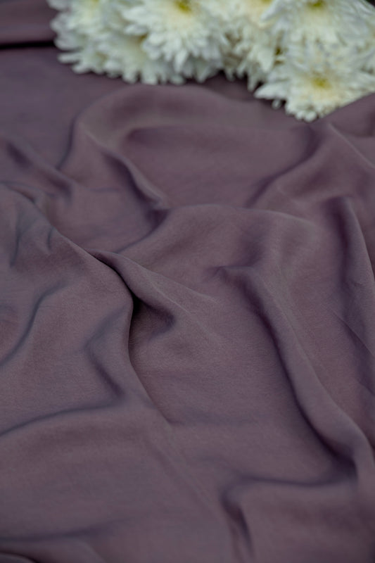 A close-up of draped dusty mauve fabric with white flowers placed in the top corner.