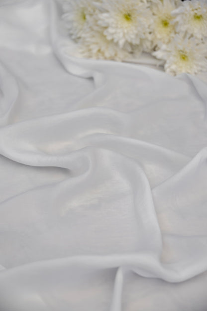White sheer chiffon fabric draped in soft folds, with white daisies placed in the upper right corner.